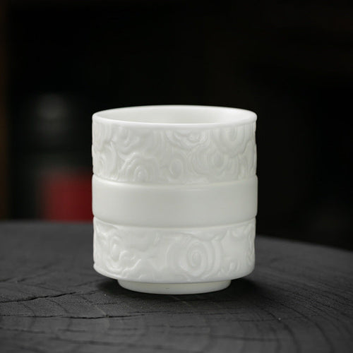 Dehua mutton-fat Jade Porcelain Master Cup Embossed with Auspicious Clouds on table